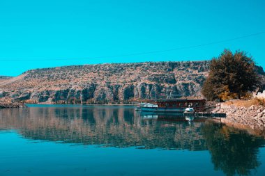 Türkiye 'nin Sanliurfa ilinde teknesi olan nehirdeki bir dağın yansıması
