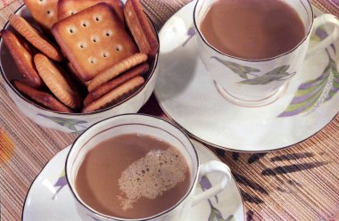 Dekoratif bir tepside iki fincan kahve ve bir kase bisküvi.
