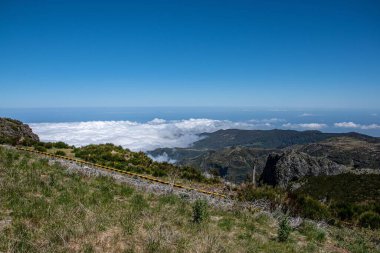 Mavi gökyüzünün altında yarı yarıya beyaz bulutlarla kaplı dağların manzarası, Madeira, Portekiz