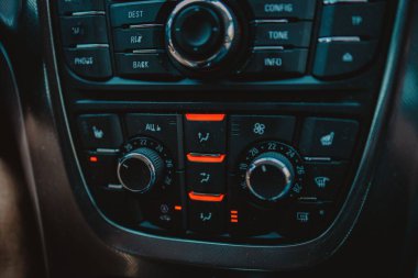 Modern bir arabanın iç dizaynının kırmızı ile aydınlatılmış ayrıntılı bir düğme paneliyle yakın plan çekimi.