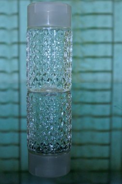 Pencerenin önündeki masada dekoratif bir su şişesi.