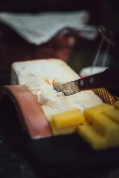 Bir Bıçağın Dikey Görüntüsü Büyük Bir Peynir Parçasına Yerleştirilmiş — Stok fotoğraf