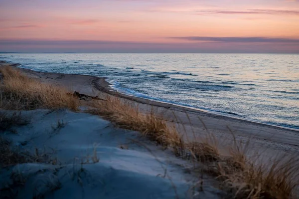 リトアニアの葦のある海岸の上に輝く黄金の夕日の空 — ストック写真