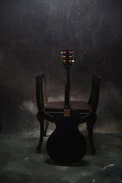 A black electric guitar on a chair