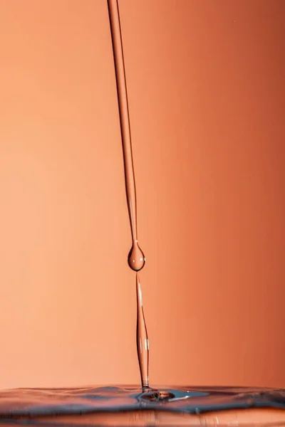 Вертикальный Снимок Жидких Капель Оранжевом Фоне — стоковое фото