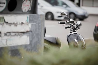 Şehir caddesinde park etmiş siyah scooter 'ın seçici odak noktası.