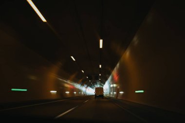 Bulanık bir tünel görüntüsü Tavanda ışıklar yansıyor Duvarlara ve beyaz bir kamyonete