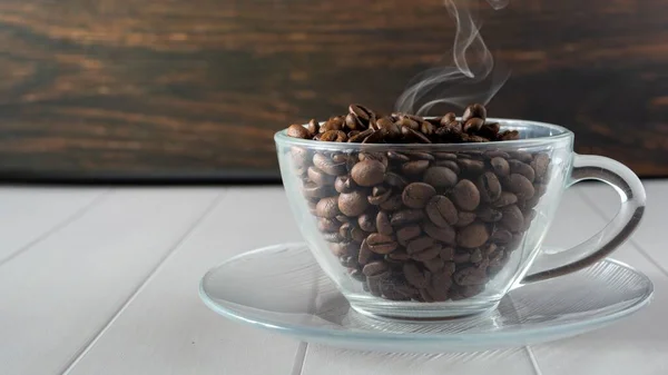 コーヒー豆のグラスカップとテーブルの上の煙 — ストック写真