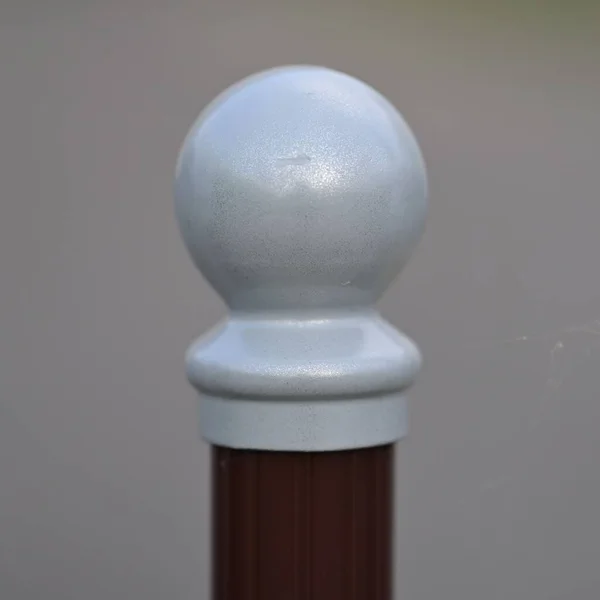 A white round tip of a signal post or a barrier