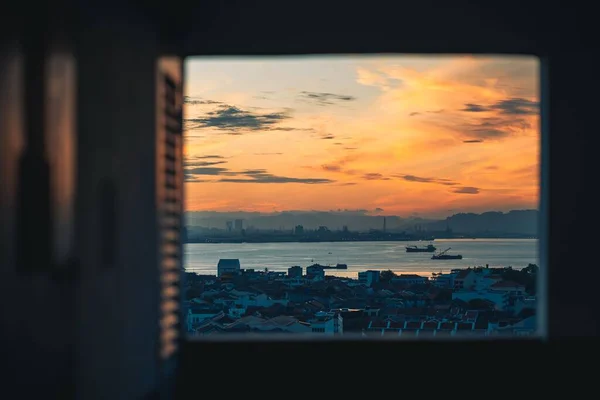 海の上に沈む夕日の息をのむような景色と 窓から正面に見える建物 — ストック写真