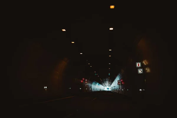 一条穿过黑暗隧道的灯火通明的道路 — 图库照片