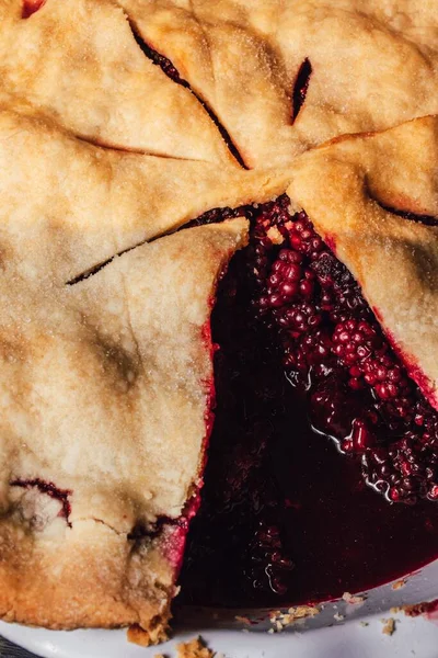 Blackberry pie with a single slice missing