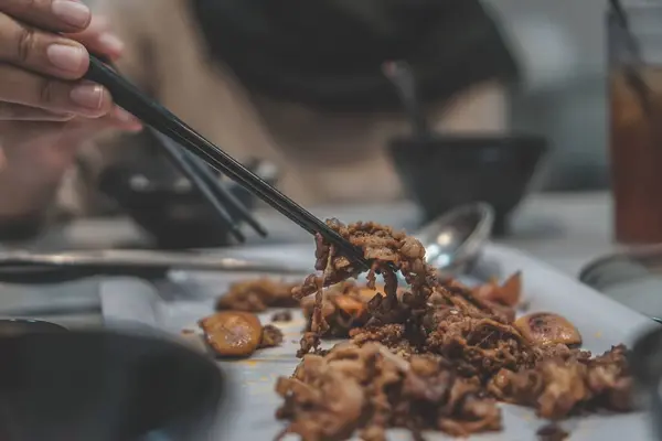 Uma Mão Segurando Carne Assada Molho Com Pauzinhos — Fotografia de Stock