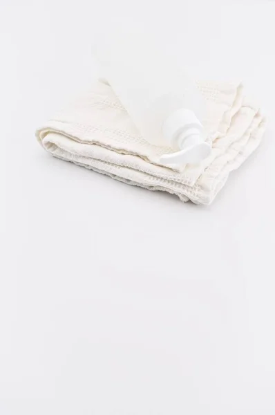 コピースペース付きの白いテーブルの上に白い綿タオルとプラスチックディスペンサーコンテナ — ストック写真