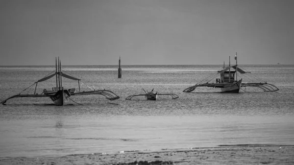 在灰蒙蒙的天空下 一只灰色的小艇在海滩附近的水里被射中 — 图库照片