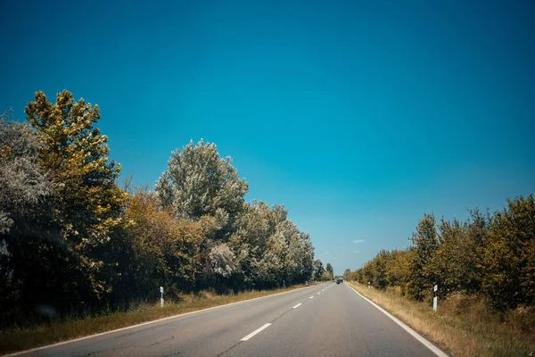 Eine Lange Asphaltstraße Durch Ein Ländliches Feld Unter Blauem Himmel — Stockfoto