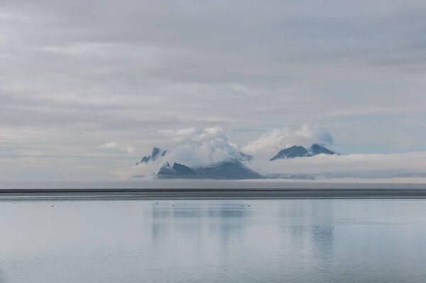 Вид с пляжа на юго-восточном побережье Исландии на скалы в облаках.