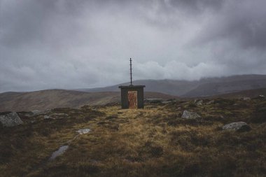 İrlanda 'da bulutlu bir günde dağlarda terk edilmiş küçük bir kulübe.