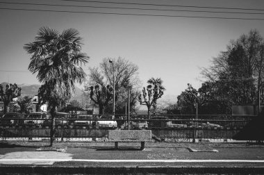 Sessiz, boş bir tren platformunun gri tonlu görüntüsü