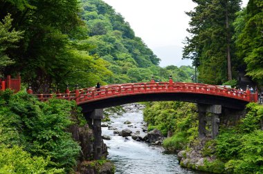 Nikko, Japonya 'daki Shinkyo köprüsünün altında kutsal bir nehir ve arka planda orman ağaçları var.