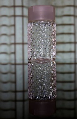 Pencerenin önündeki masada dekoratif bir su şişesi.