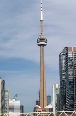 Toronto şehir merkezindeki CN kulesinin dikey görüntüsü. Mavi gökyüzü ve etrafındaki binalar.