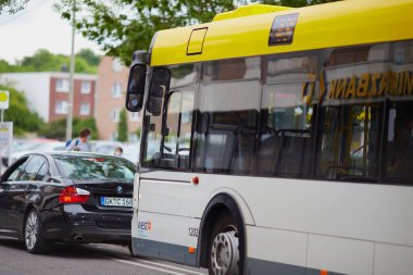 Önünde sarı bir otobüs ve BMW bir araba Almanya 'nın Geilenkirchen şehrinde gündüz vakti bir caddede sürüyor.