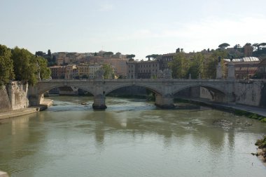 Roma 'daki Tiber nehri İtalya' da Ponte Vittorio Emanuele köprüsü ile arka plandaki kıyıları ve konut binalarını birbirine bağlıyor.