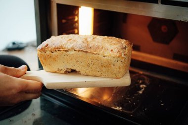 Fırından taze pişmiş ekmek çıkartan birinin ellerine yakın çekim.