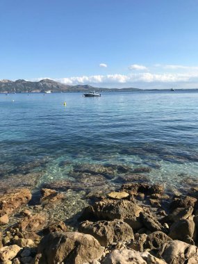 Mallorca 'da güneşli bir günde açık mavi Akdeniz ve kayalık bir sahilin dikey görüntüsü.