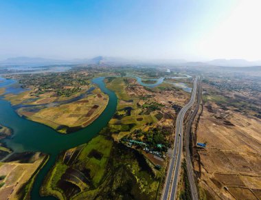 Ağaçlar ve nehirle çevrili bir yolu olan yüksek açılı bir manzara.