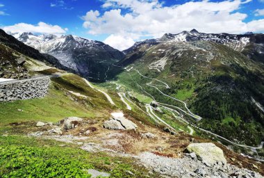 Mavi bulutlu gökyüzüne karşı güzel yeşil dağların manzarası.