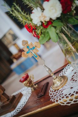 Bir ahşap haçın dikey görüntüsü ve bir düğün töreni için masanın üzerinde bir buket var.