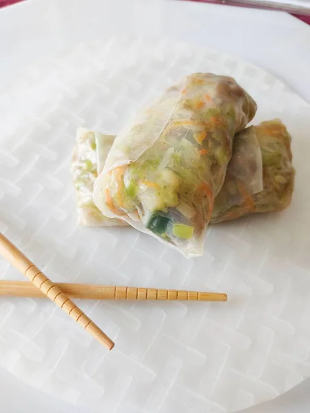 A vertical shot of Rice paper rolls with wooden sticks on white plate