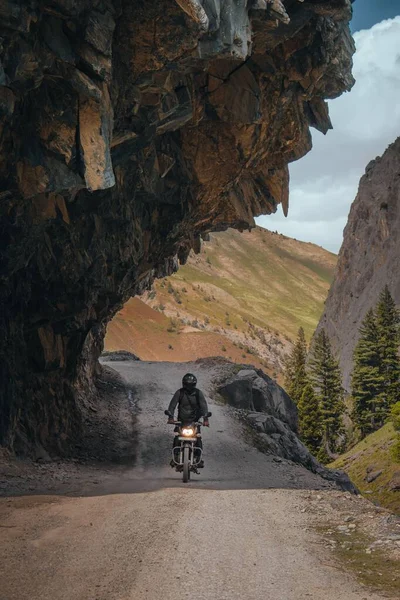 Pionowe Ujęcie Motocyklisty Kaskiem Jadącego Rowerze Drodze Pod Klifem — Zdjęcie stockowe