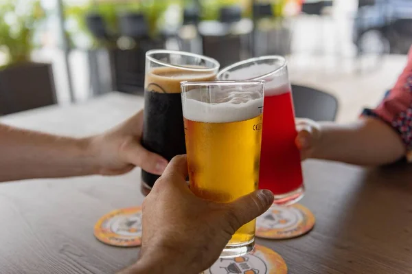 パブのテーブルの上に異なるクラフトビールのグラスを投げる男性のグループ — ストック写真