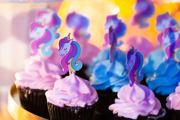 A selective focus shot of chocolate unicorn cupcakes on a golden tray with blur background