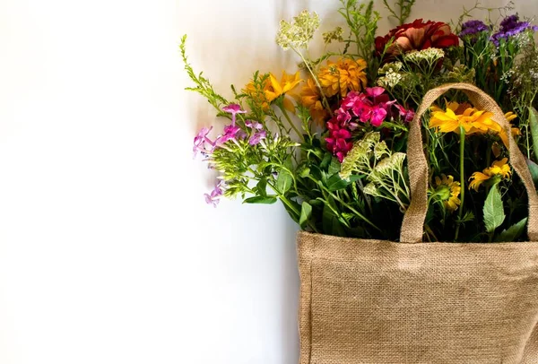 A bunch of beautiful flowers in a burlap bag isolated on a white background