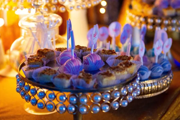 A decorated chocolate unicorn cupcakes on a golden tray with blur lights background