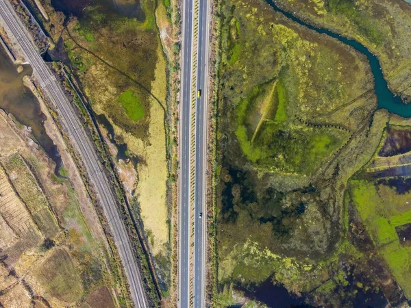 A bird\'s eye view of a highway stretching through a beautiful landscape with forests