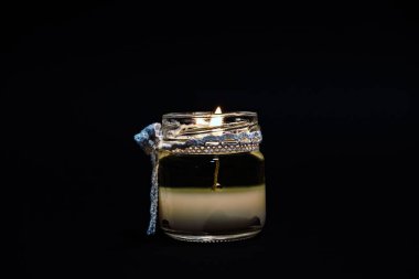 Yanan cam mum siyah arkaplanda izole edilmiş.