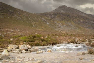 Güzel bir kayalık nehir manzarası ve bulutlu bir günde dağlar.