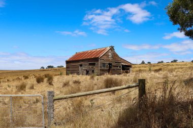 Kuru otlarla dolu bir tarlada eski ahşap bir evin güzel manzarası.