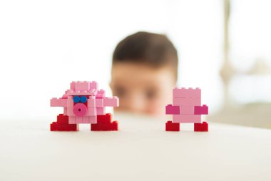 Kirby modellerinin legodan yapılmış seçici bir odak fotoğrafı ve bulanık arkaplanlarına bakan bir çocuk.