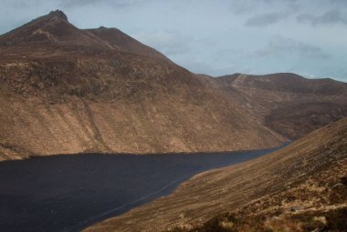 Bulutlu bir günde gölü olan güzel bir dağ manzarası.