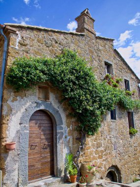 İtalyan kırsalındaki taştan bir evin dikey görüntüsü.