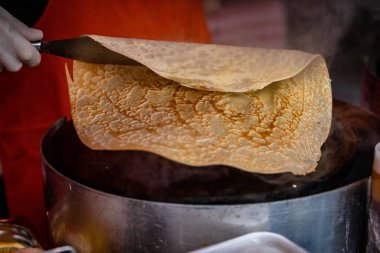 Bir elin yakın çekimi, tavada lezzetli bir gözleme hazırlıyor.