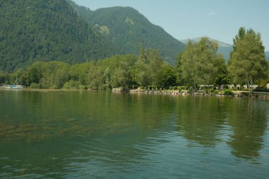 Sudaki ağaçların yansımasıyla sakin bir göl manzarası.