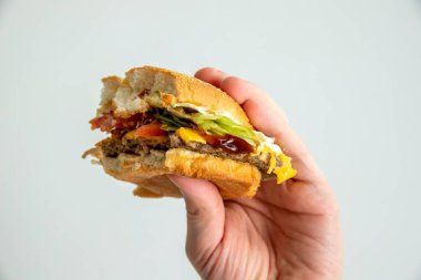 Lezzetli bir burgeri tutan bir adamın yakın çekimi.