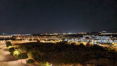 Gece aydınlanmış şehir manzarasının koyu mavi gökyüzü arkaplanına karşı çatı manzarası
